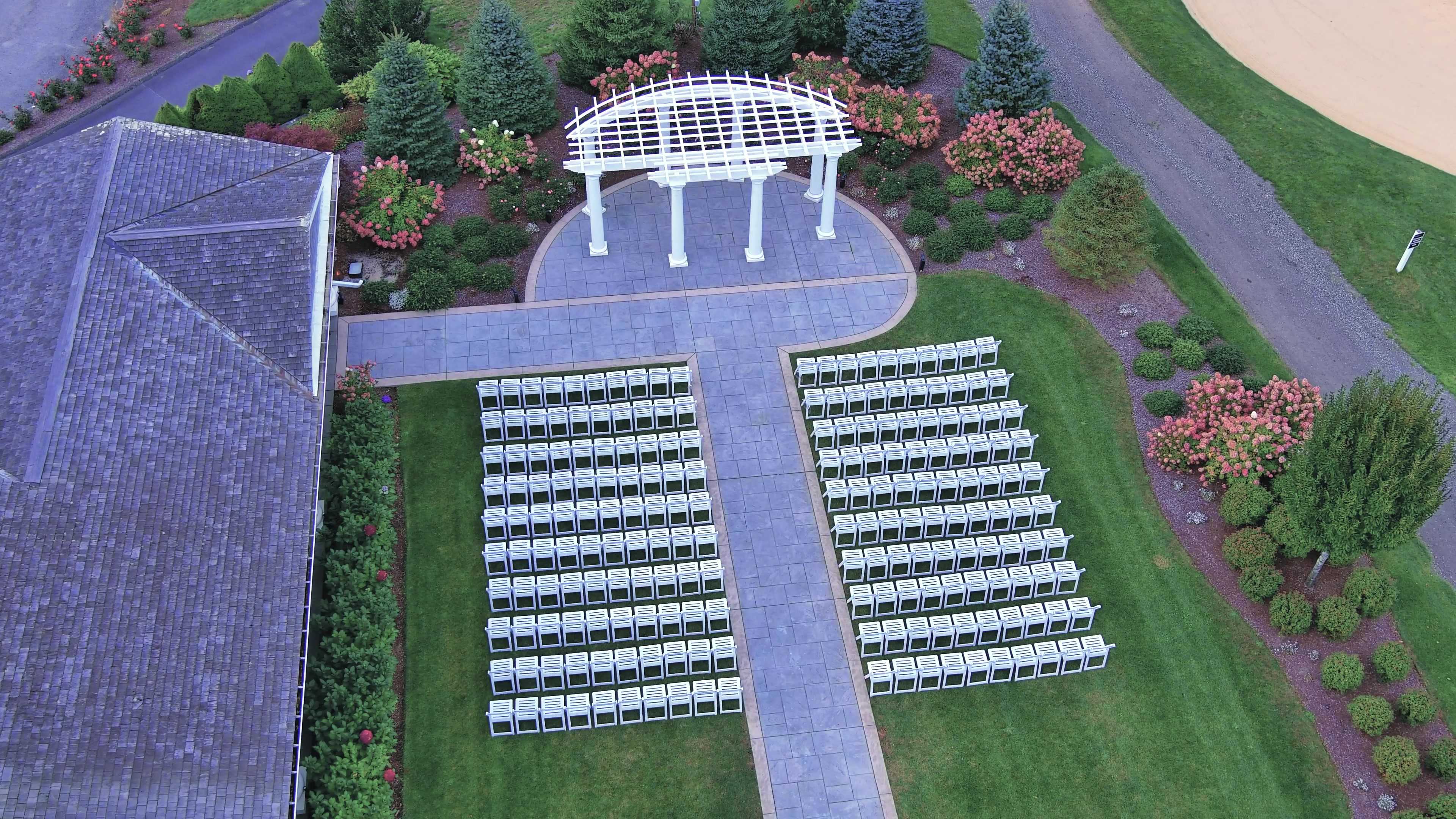 Drone view of a ceremony pergola and rows of white chairs